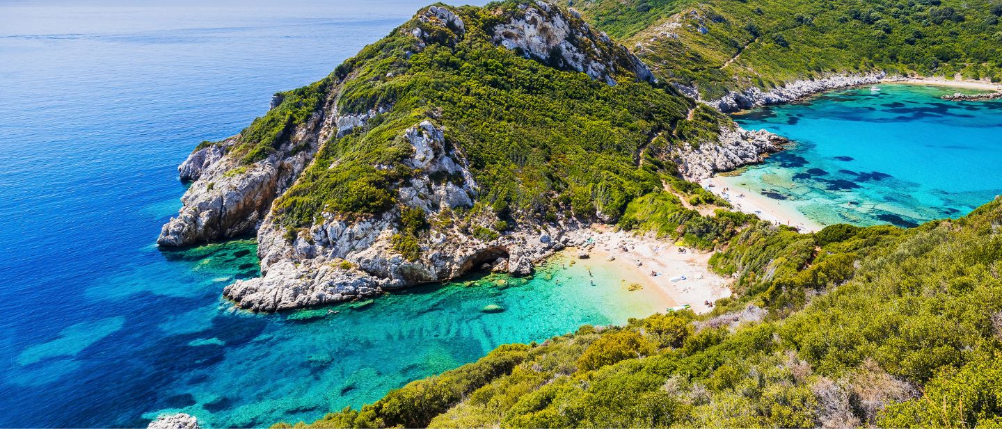 Dvi įlankos su skaidriu turkio spalvos vandeniu ir žaliuojančiomis uolomis Korfu pakrantėje