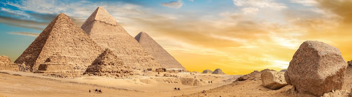Didžiosios Egipto piramidės smėlio dykumoje po auksiniu saulėlydžio dangumi