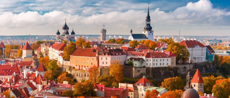 Estijos senamiesčio panorama su raudonais stogais, bažnyčių bokštais ir spalvingais rudenio medžiais