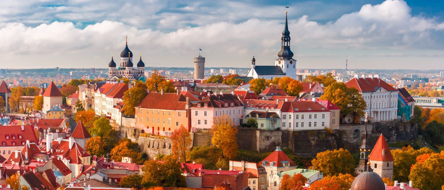 Estijos senamiesčio panorama su raudonais stogais, bažnyčių bokštais ir spalvingais rudenio medžiais