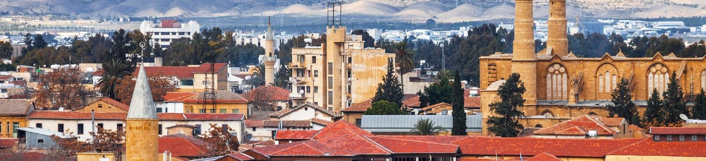 Nikosijos miesto panorama su raudonais stogais, minaretais ir kalnais fone