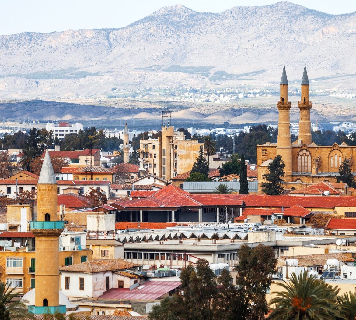 Nikosijos miesto panorama su raudonais stogais, minaretais ir kalnais fone
